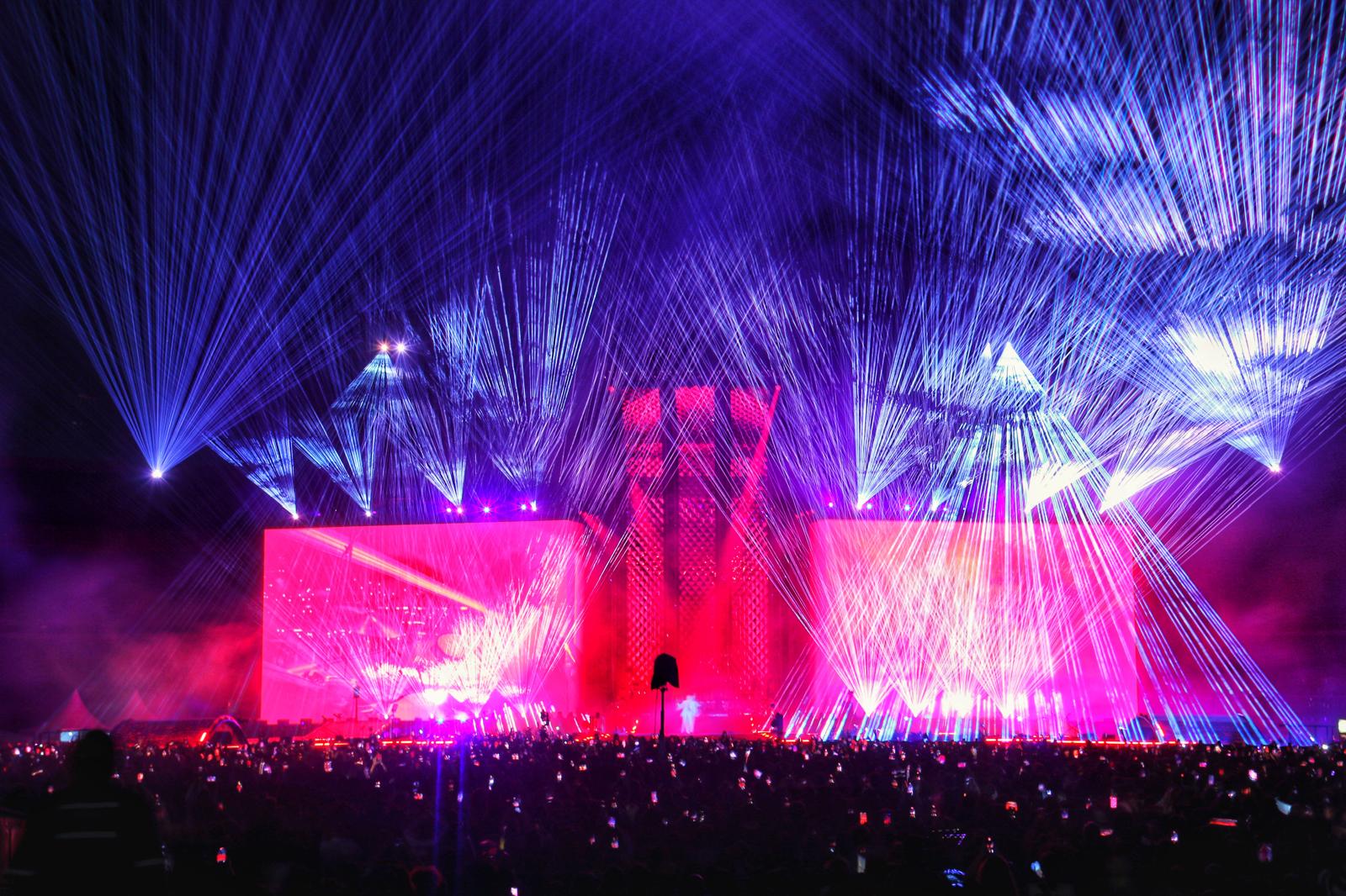 Blue and pink laser beams enveloping a stadium stage