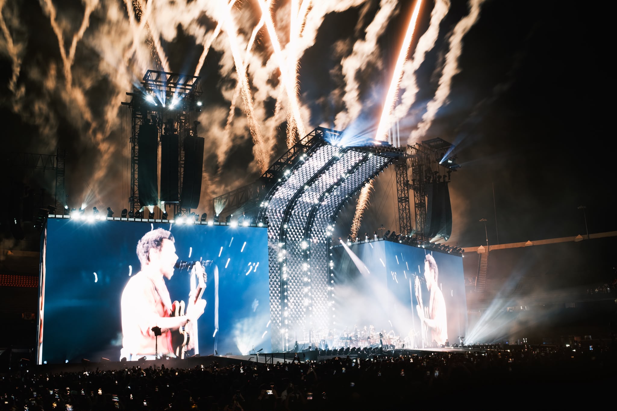 Large stadium production with pyrotechnics firing above the stage