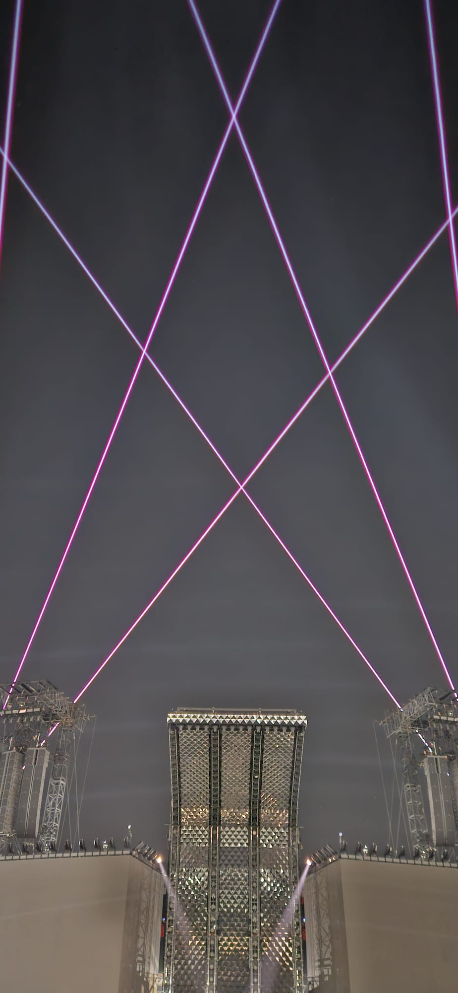 Pink laser beams crossing above a stadium stage