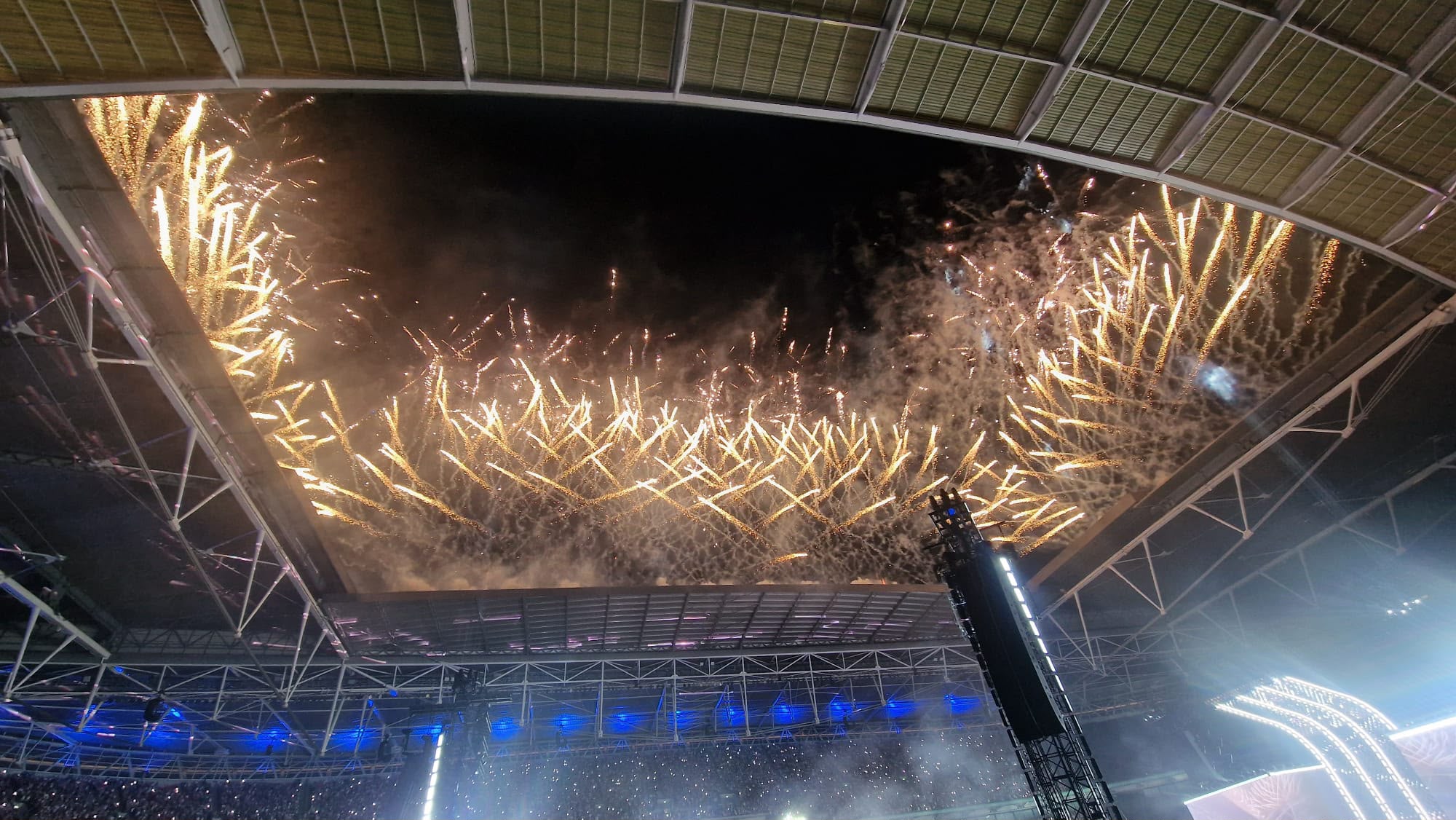 Golden pyrotechnics firing across an open stadium roof