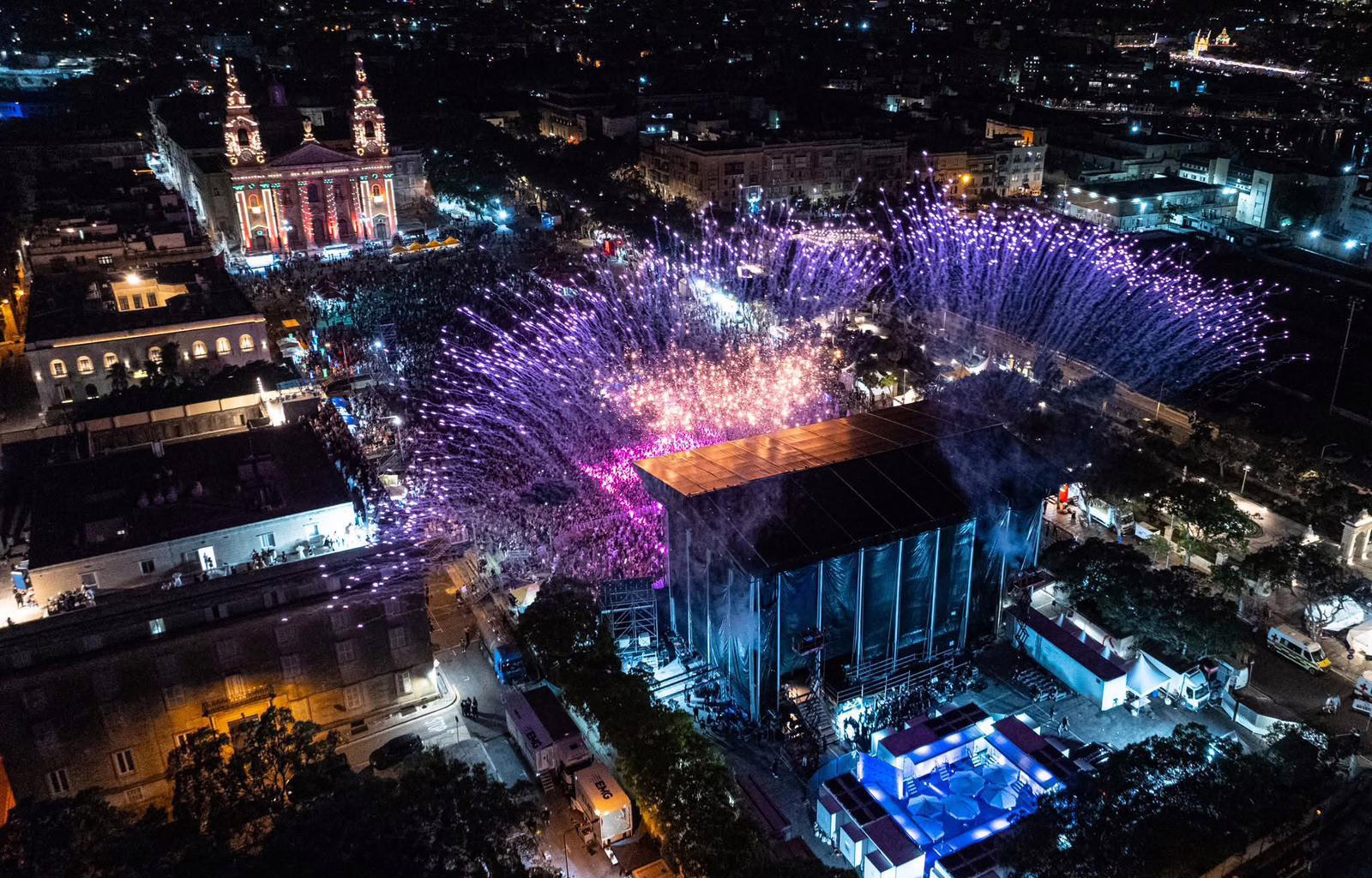 Aerial view of a city concert surrounded by purple pyrotechnics
